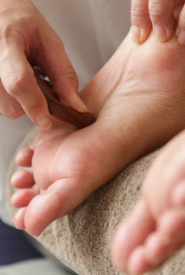 Client receiving acupressure reflexology treatment with wooden points massager stick. Natural medicine, reflexology, acupressure foot massager oppresses energy flow points